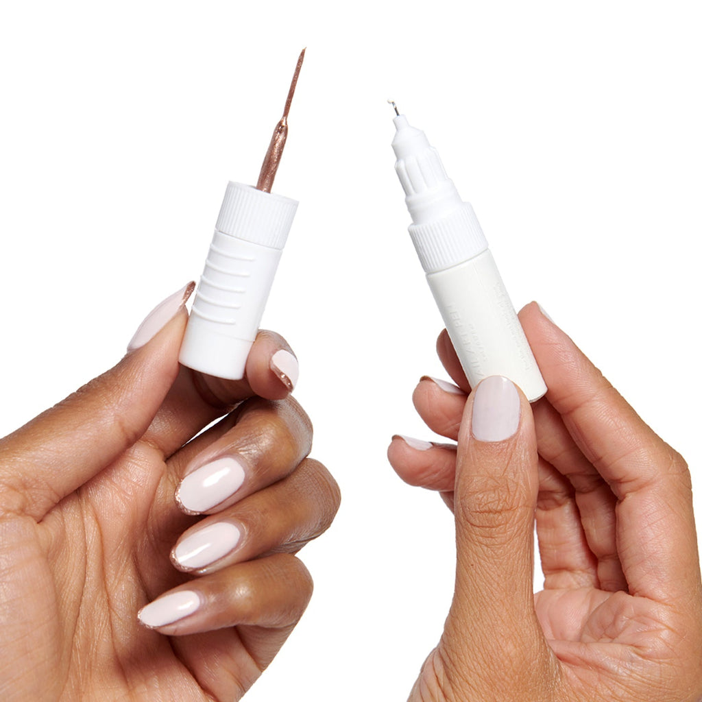 Hands holding a double-sided Nail Art Pens tool with fine tip and brush for detailed at-home manicures